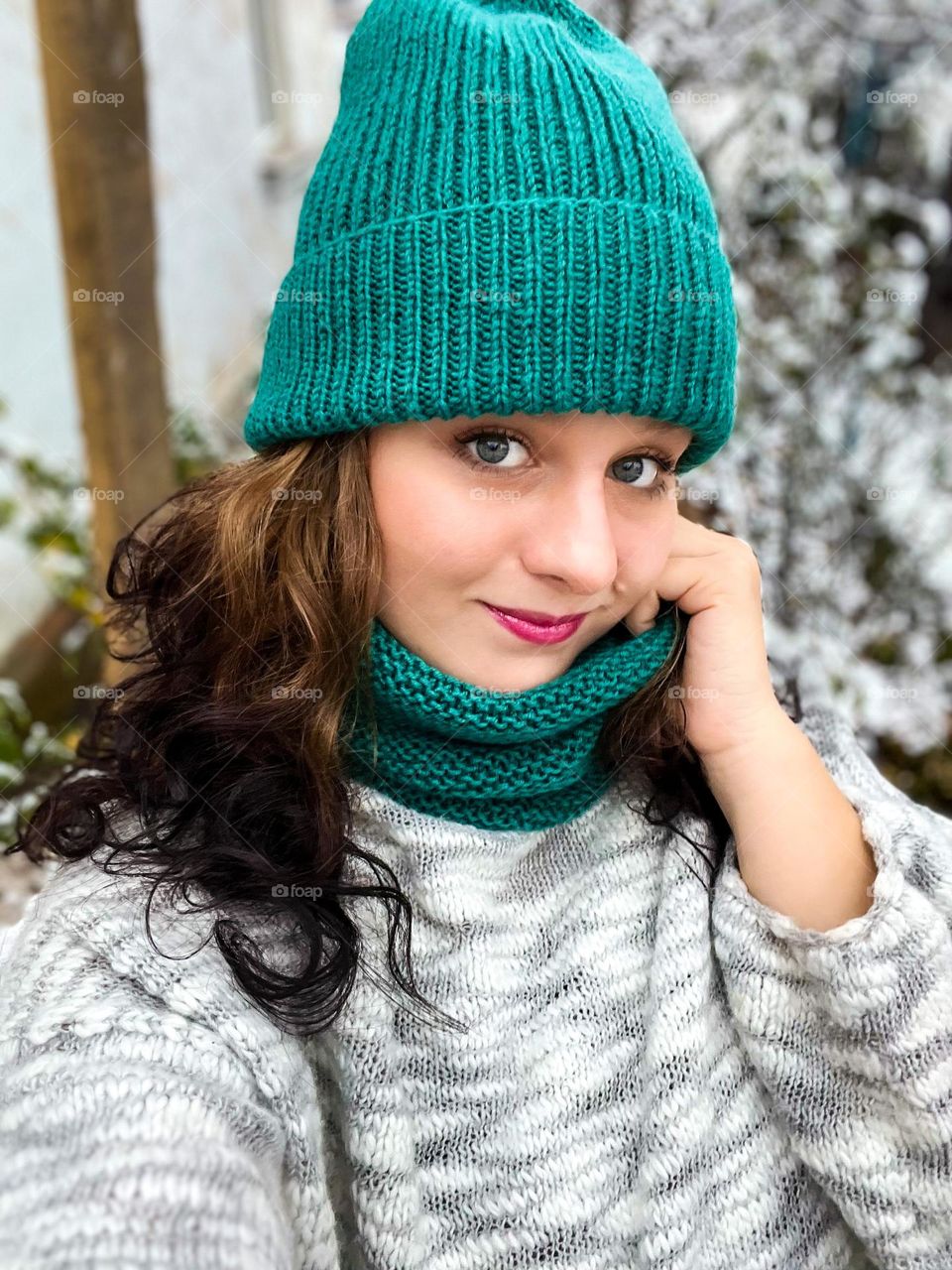 Winter vibes self portrait of cute girl with blue eyes in a green knitted scarf and hat