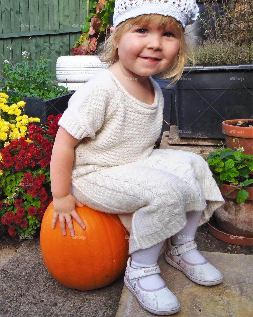Cute girl sitting on pumpkin