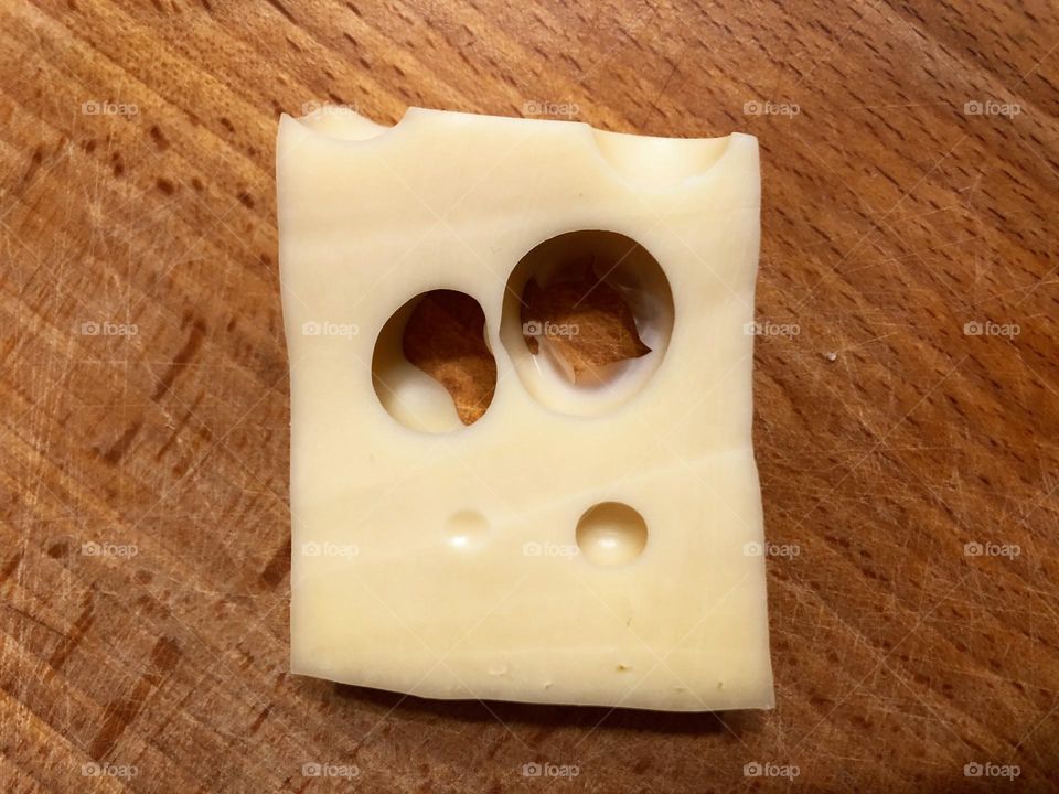 Cheese with circles as a face with big eyes and mouth 