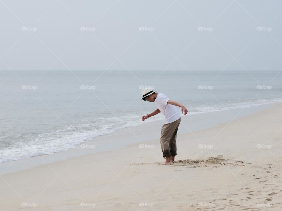 A teenager playing on the sandy beach in Teluk Cempedak, Malaysia