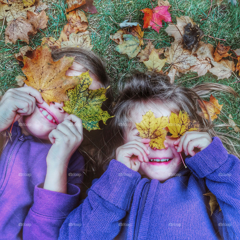 Two girls lying on autumn leaves