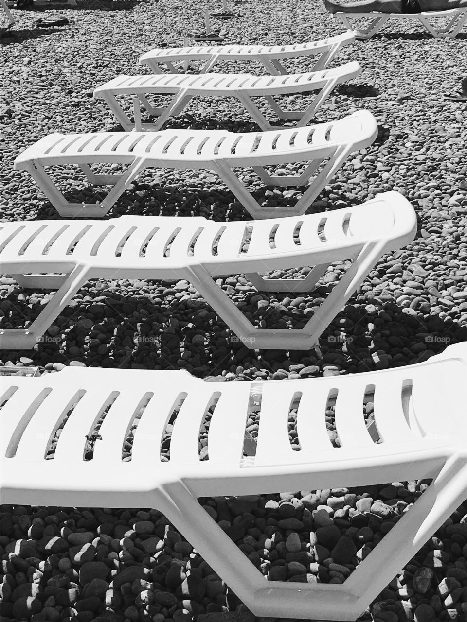Beach, sand, stones, white chairs, row. Summer, sea, rest, vacation