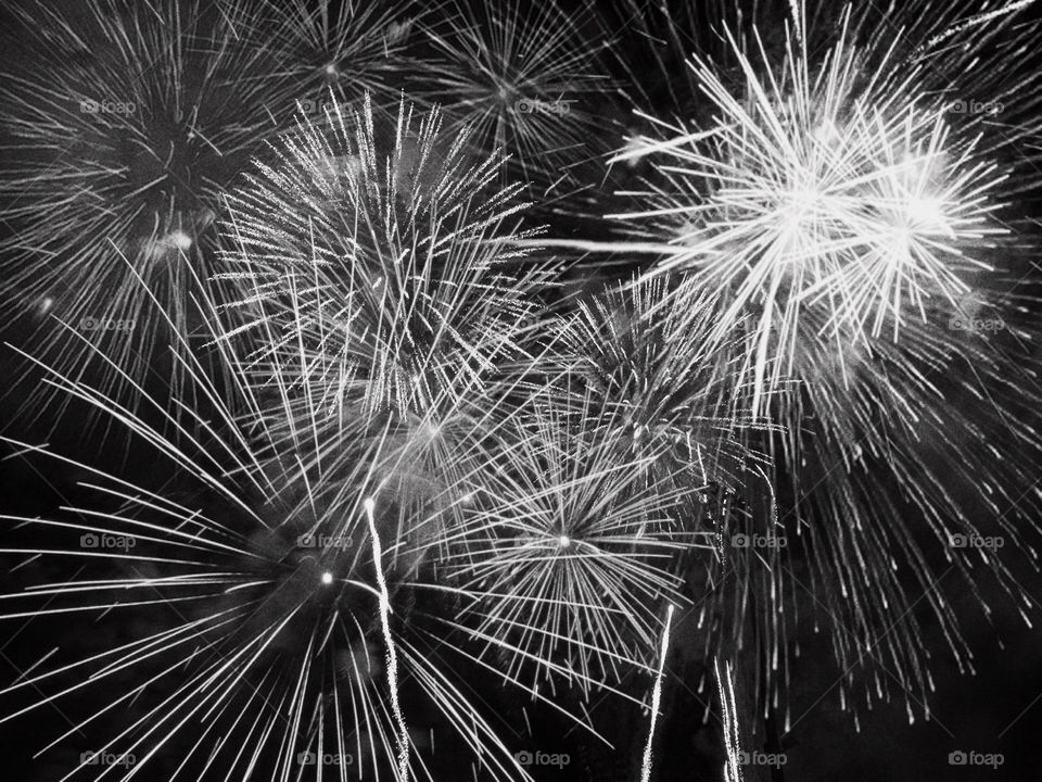 Beautiful fireworks lighting the night sky in a black and white photo.