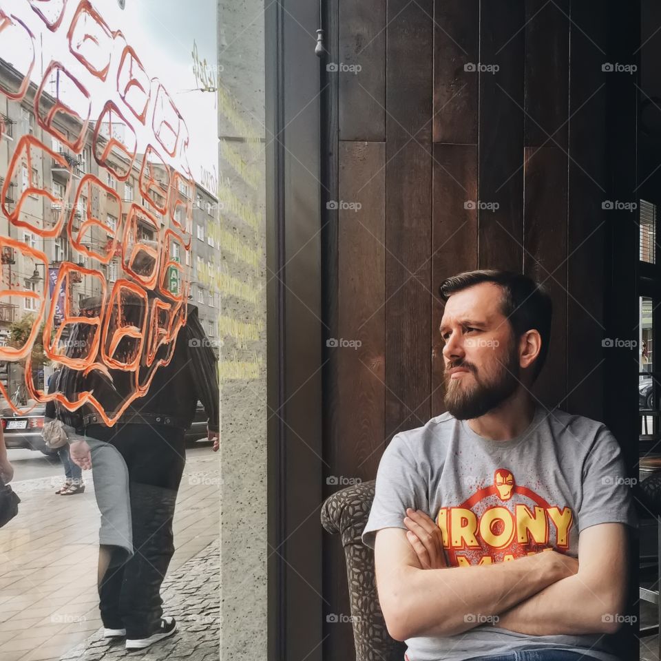 Beard man looking at street through glass window