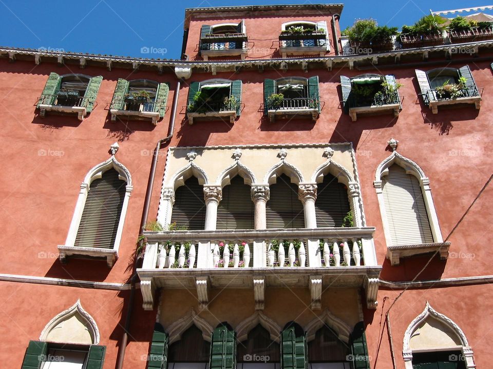 Venetian building with red exterior and ornate windows and balcony 