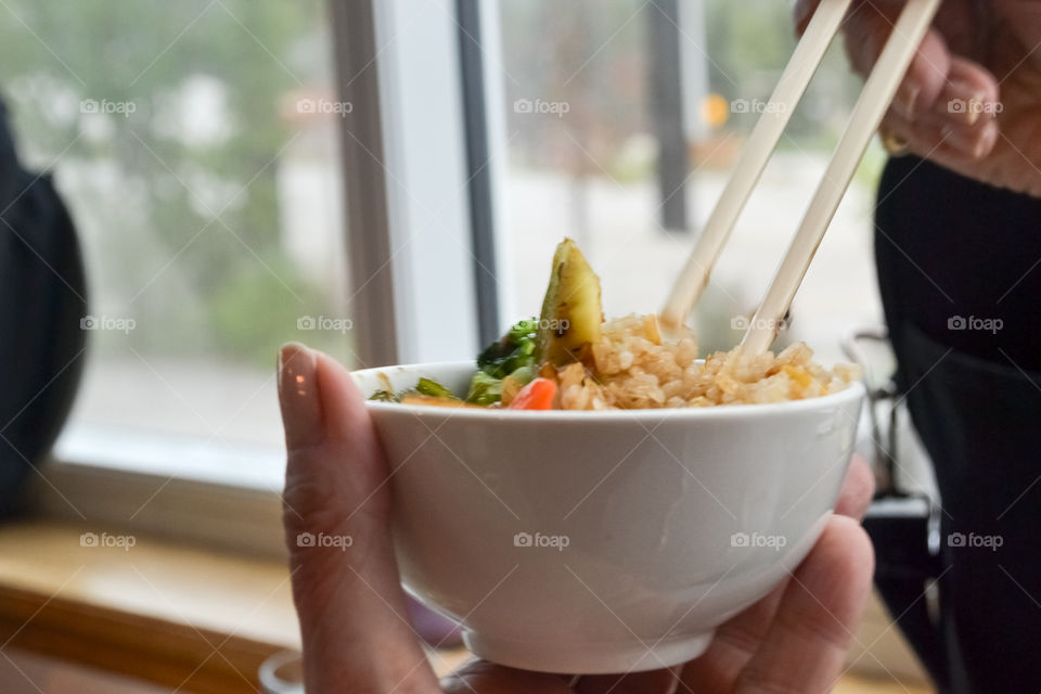 Woman eating bowl of chine stir fry vegetables