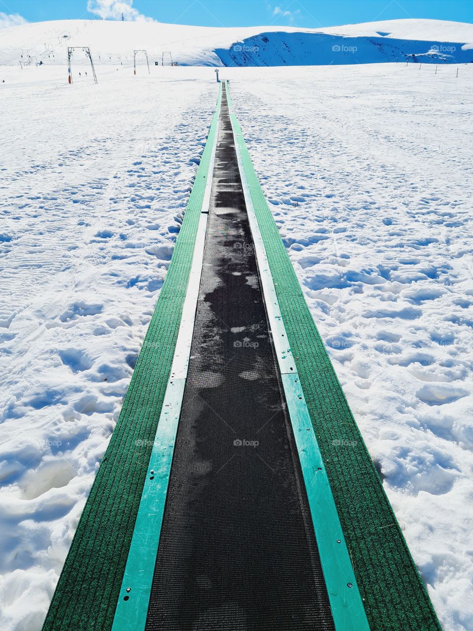 green conveyor belt for skiers on white snow