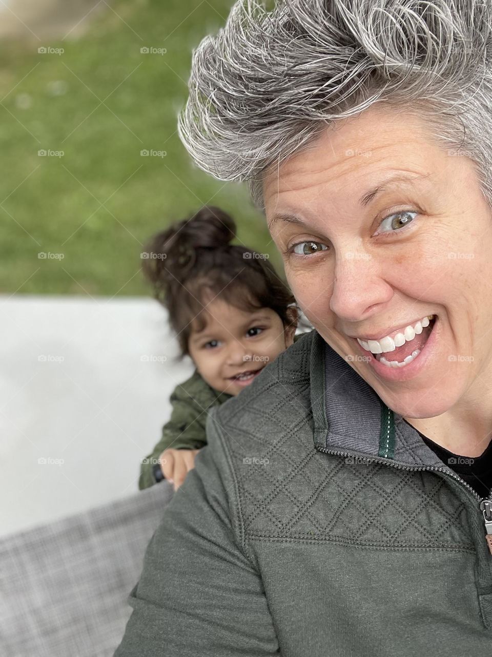 Toddler peeks over shoulder of mommy, mommy and toddler girl smiling and laughing, emotion of happiness portrayed by family, mommy and toddler time, family time, cute peek a boo image, toddler being sneaky, cute toddler girl and mommy are happy