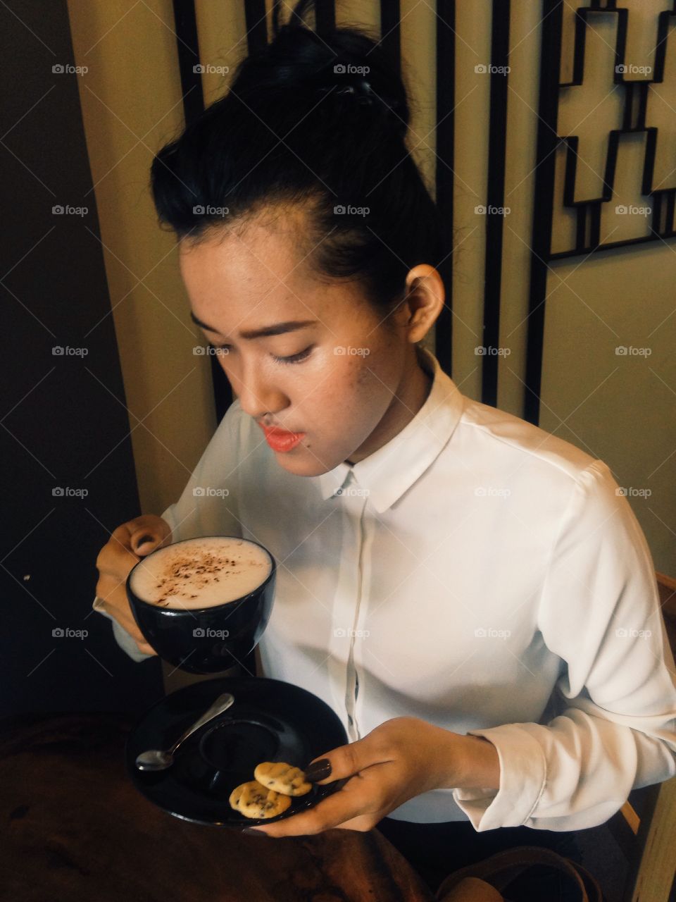 Young waitress holding cup of coffee with cookie