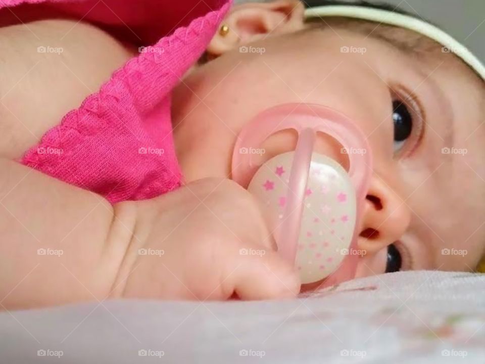 Baby wearing pink clothes and pacifier