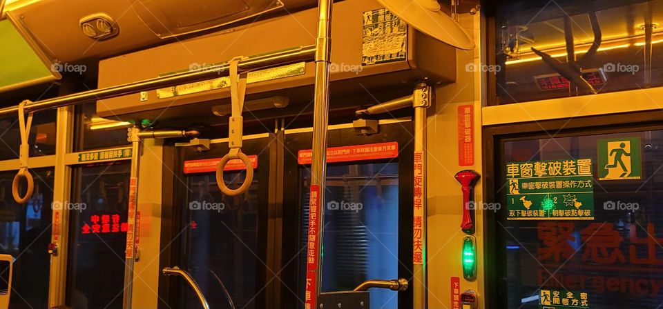 A retro-style bus with a warm yellow light interior.Safety equipment window breakers.bus seat.card reader.handrail ring