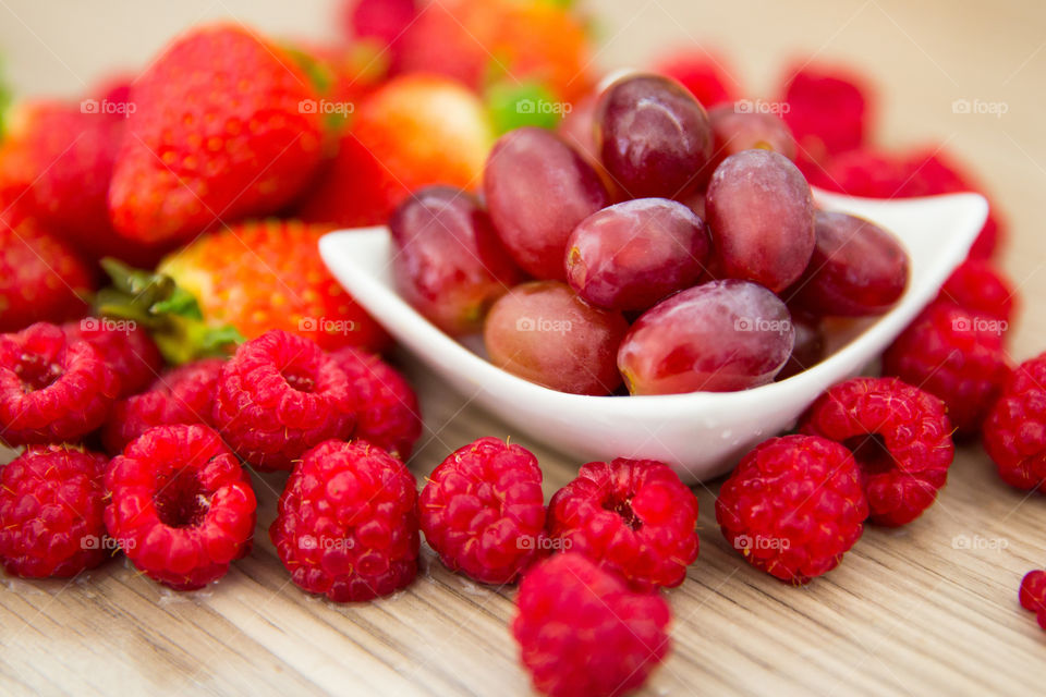 I love eating to improve my health. Fresh fruit with raspberries grapes and strawberries. Close up of fresh red summer fruit.