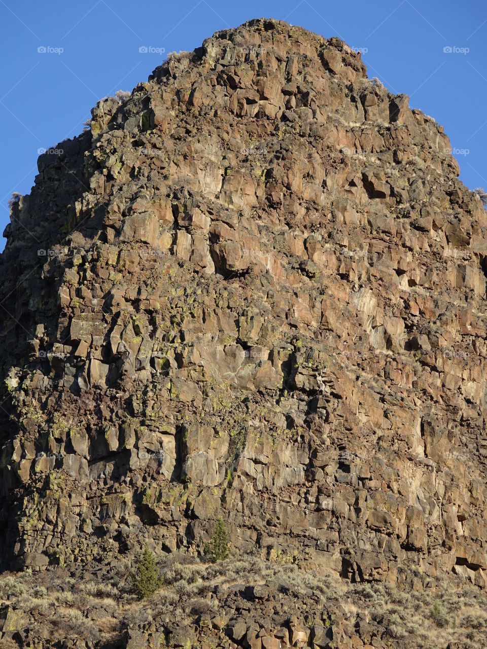 Jagged geology bursts from a hilltop on a sunny day in Crook County in Central Oregon. 