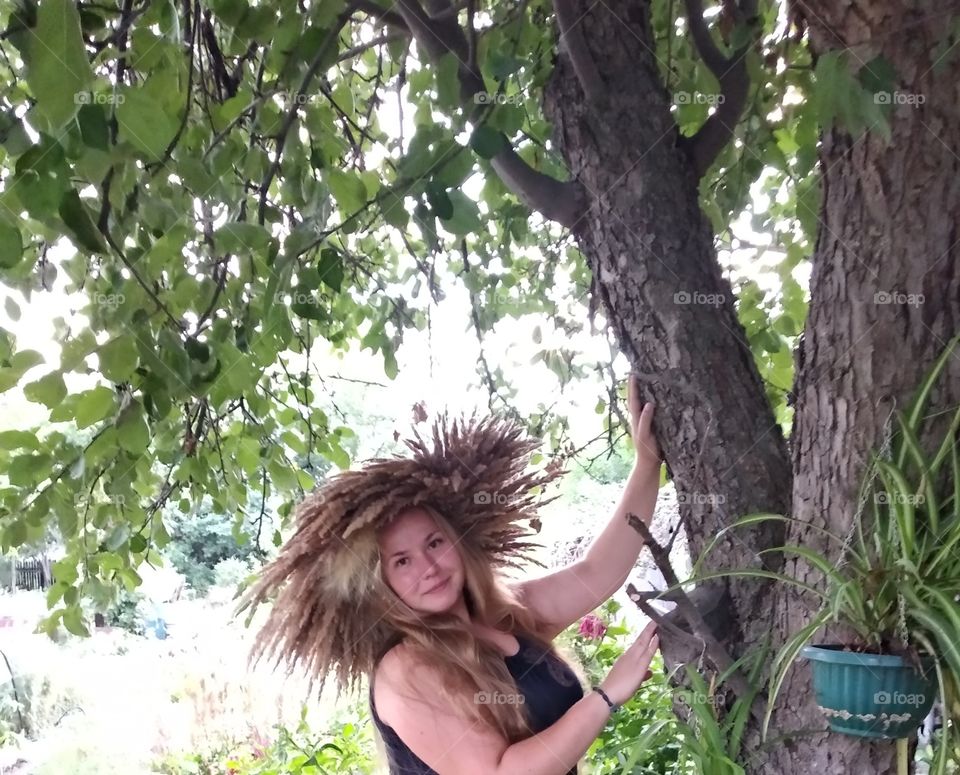 Lush girl with a wreath on her head near a tree