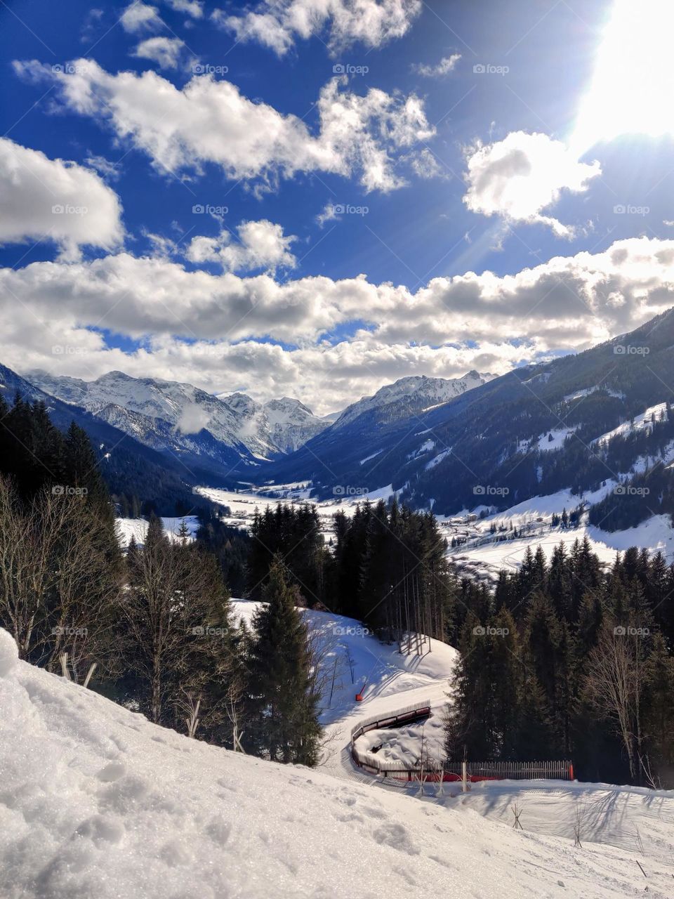 Snowy valley in the mountains of Salzburg, Austria. Blue skies with clouds and a lot after trees surrounding the valley