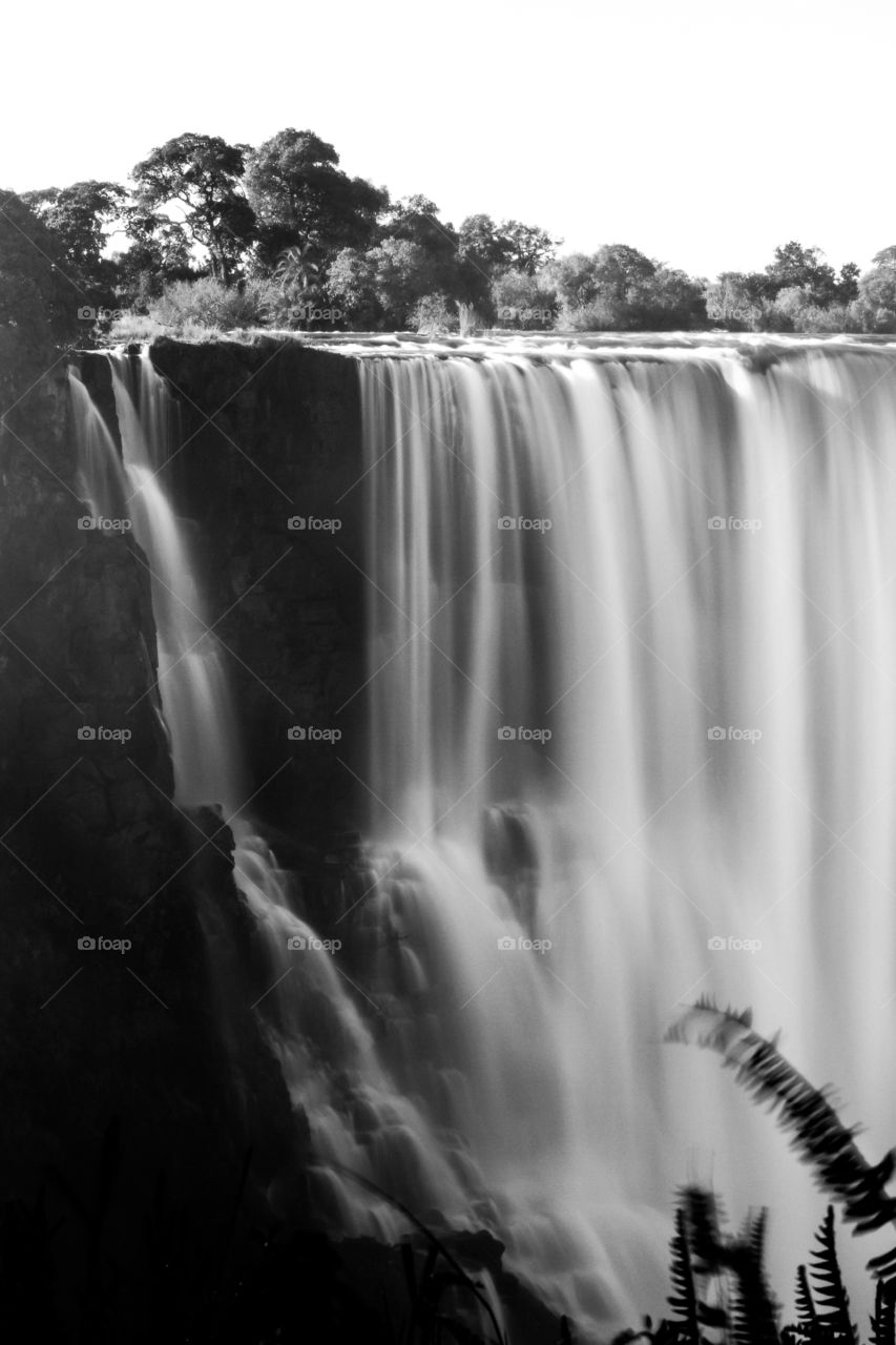 Close up of slow water falling at majestic waterfall in Africa. Black and white image