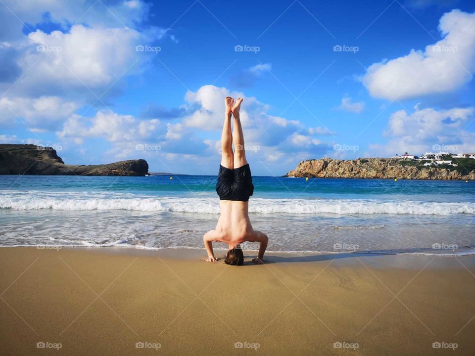 Headstand on sandy beach in menorca 