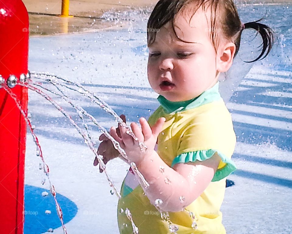 A little girl standing near drinking fountain