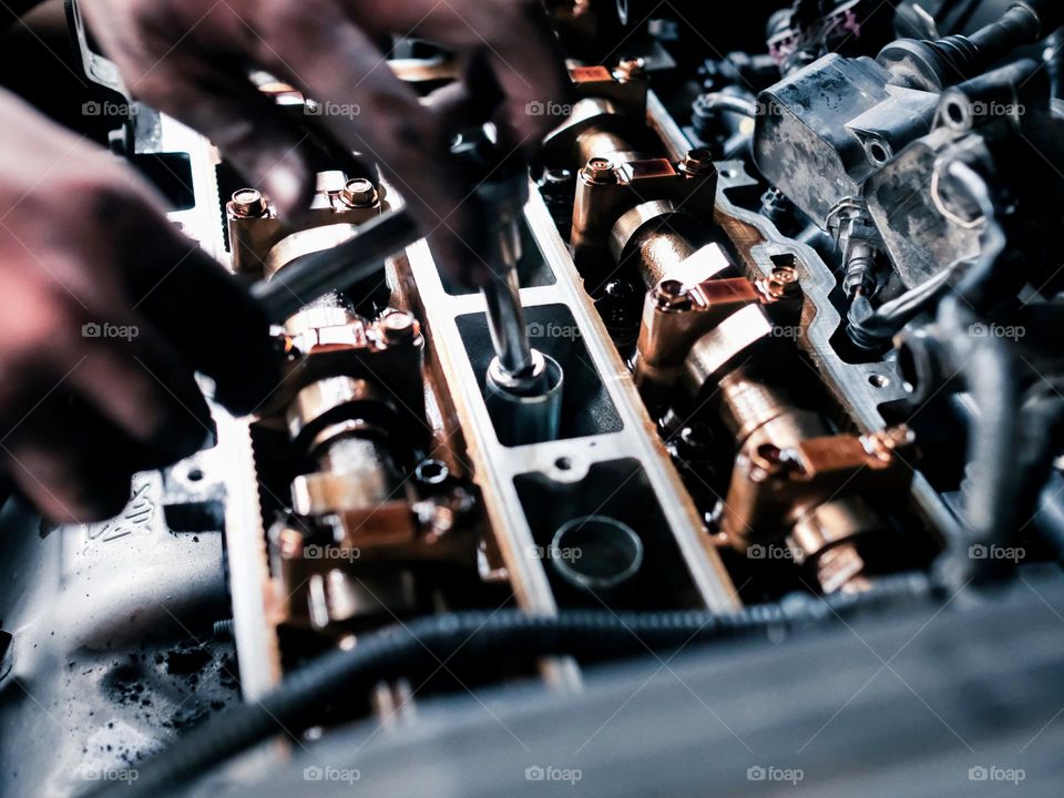 Close-up view of a pair of hands working on a car engine top