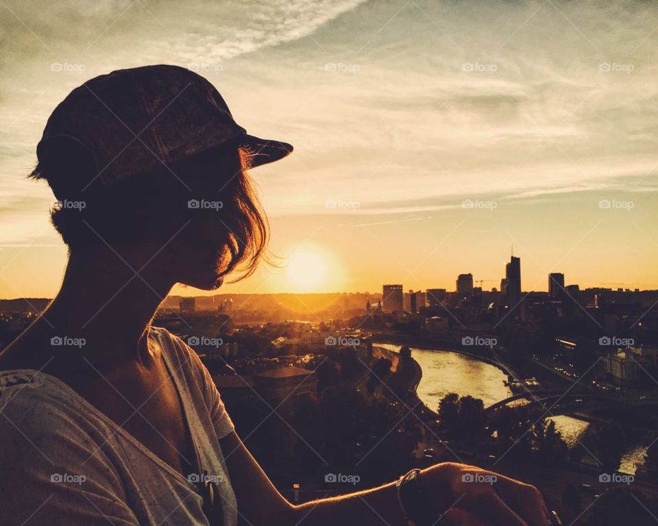silhouette of girl watching sunset above the city of Vilnius.