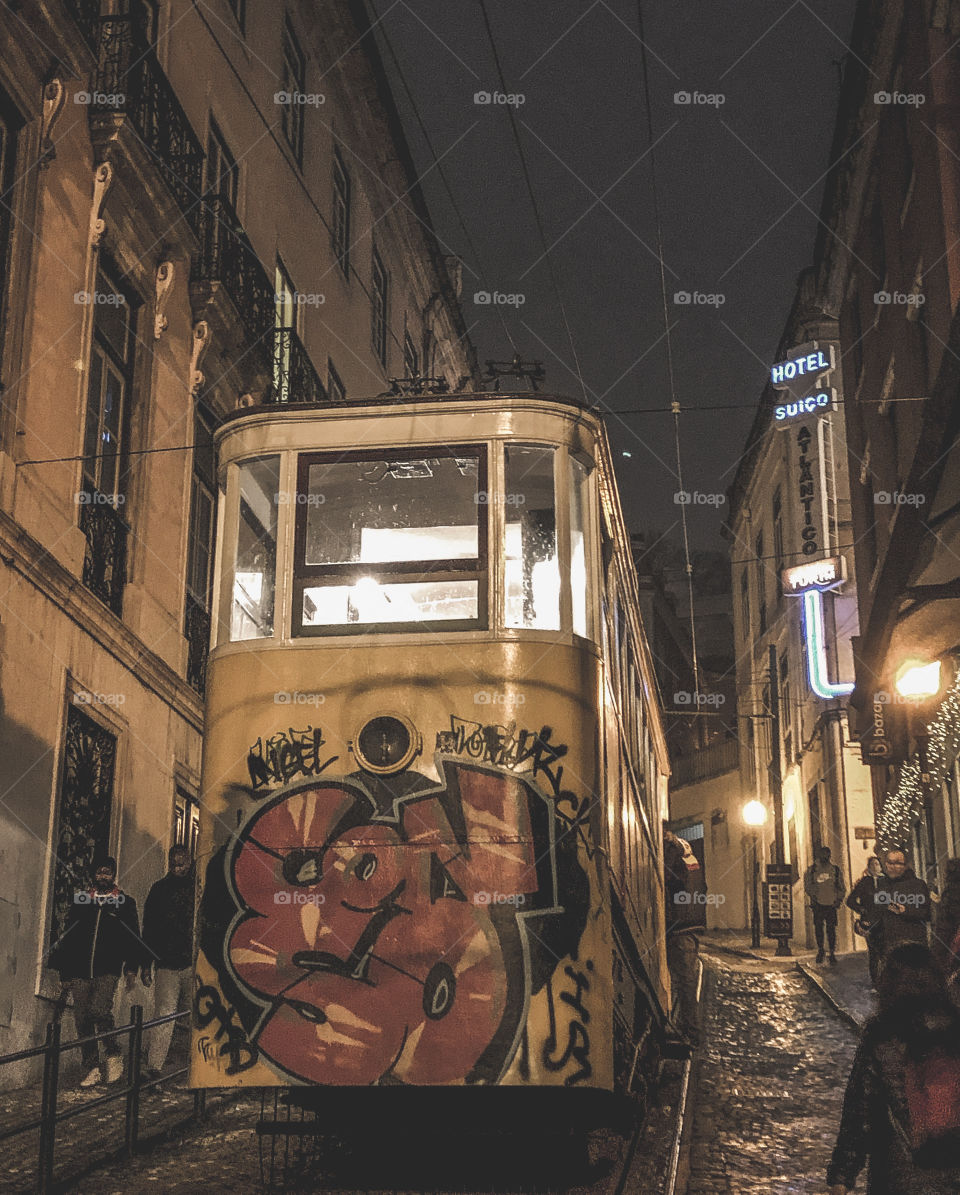 A graffitied funicular makes the steep ascent towards Hotel Suiço on a rainy night in Lisbon