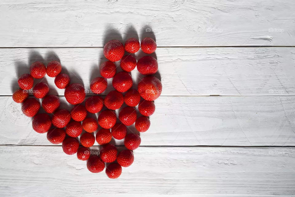heart of red strawberries on a white wooden background from boards.  flatley, copyspace, valentines day 