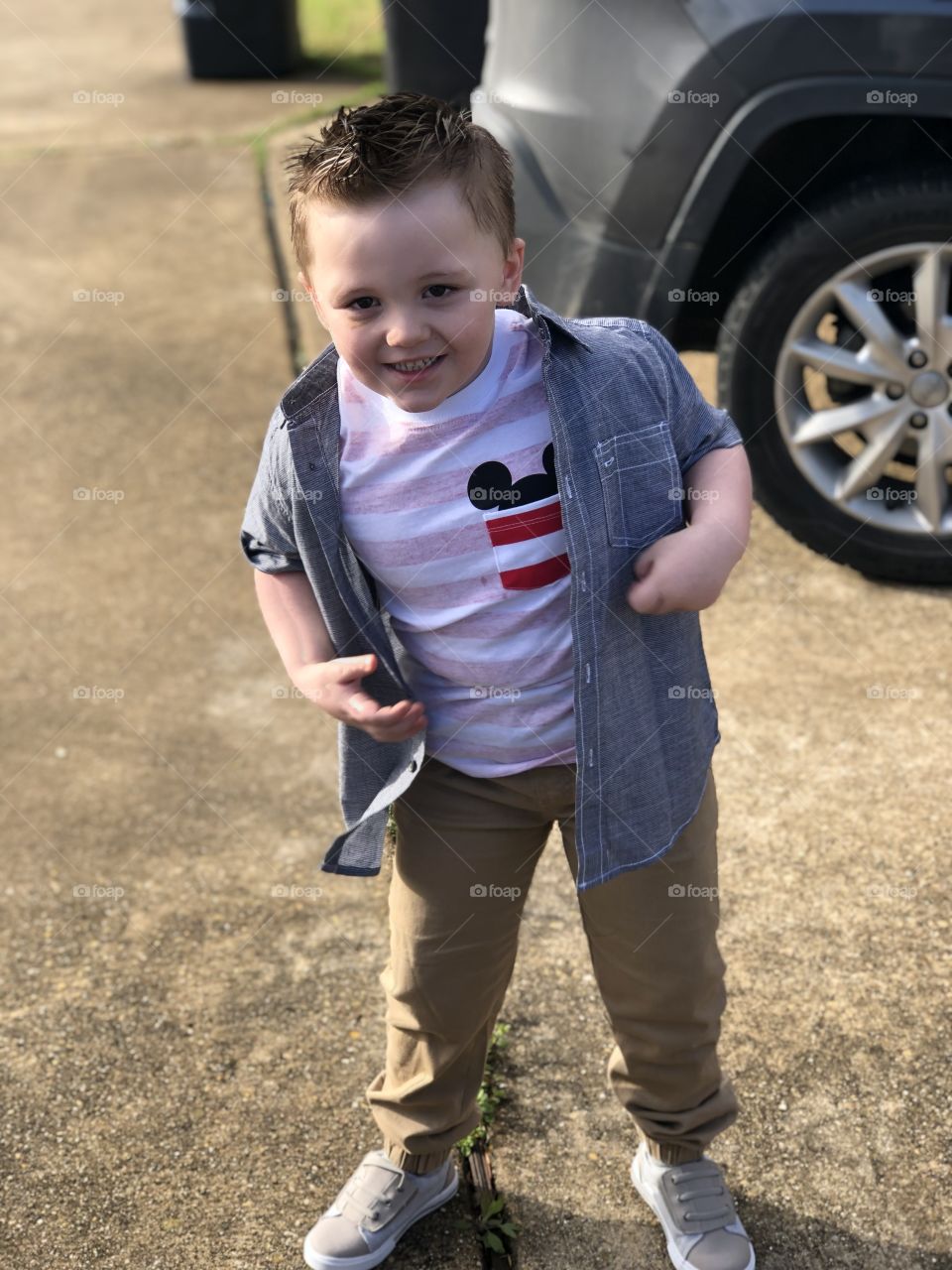 Happy toddler playing outside in the sun. Dressed up sharp, calls his own style a “rockstar”