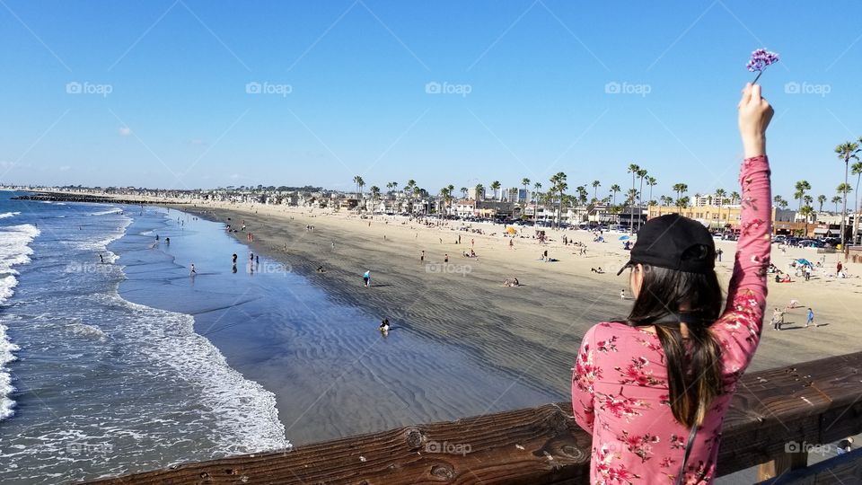 fashionable woman looking out the sea view of the ocean holding up a flower