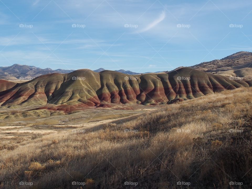 The textured Painted Hills in Eastern Oregon with layers of red, brown, green, and yellow on a sunny winter afternoon. 