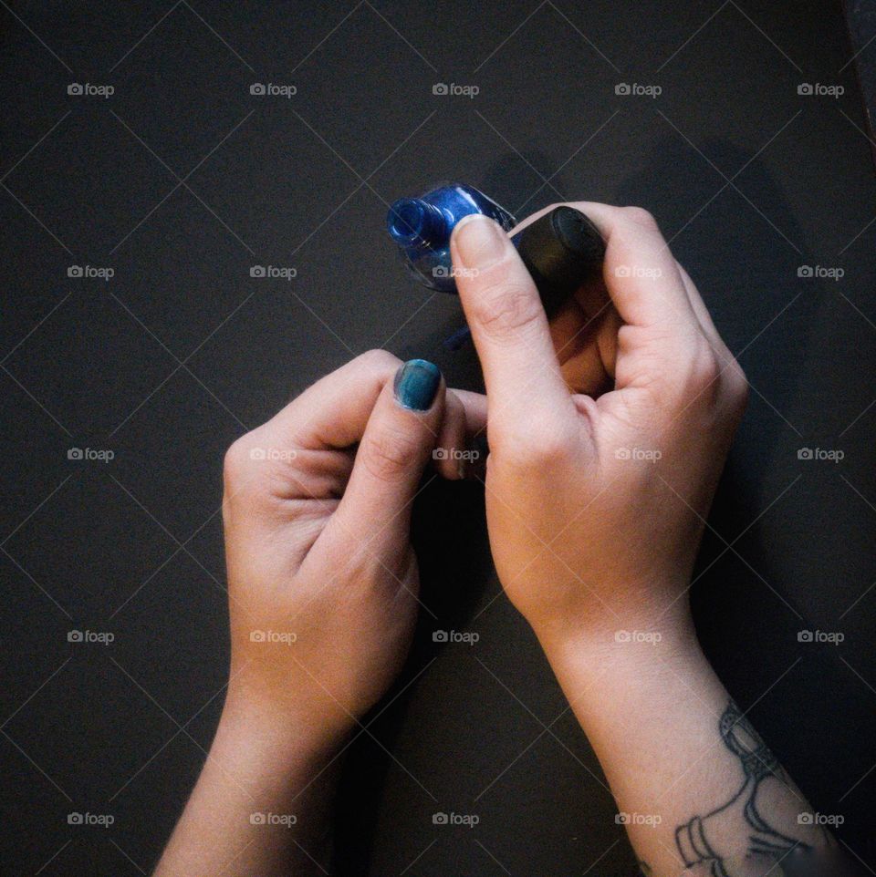Dark blue nail polish being applied