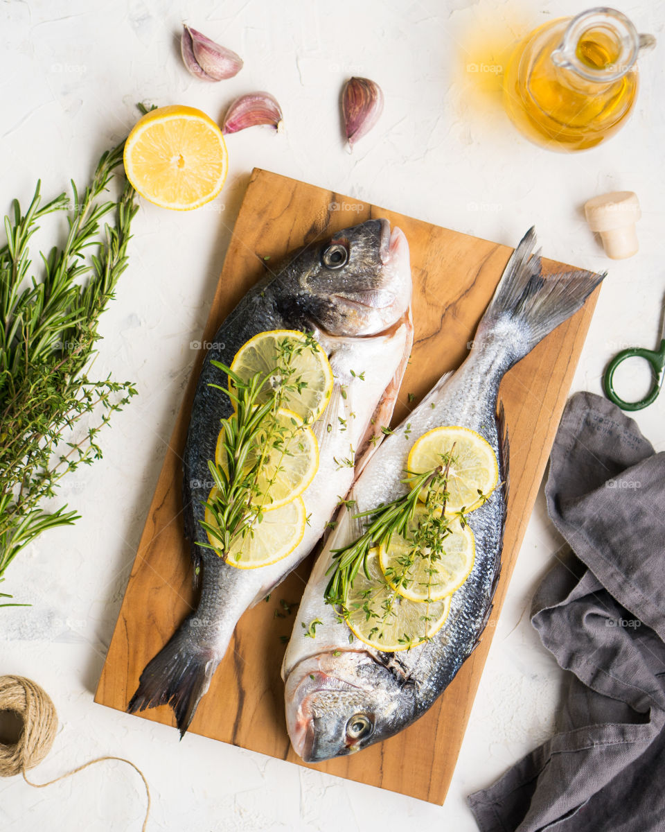 Cooking Dorado Fish with lemons and herbs, top view