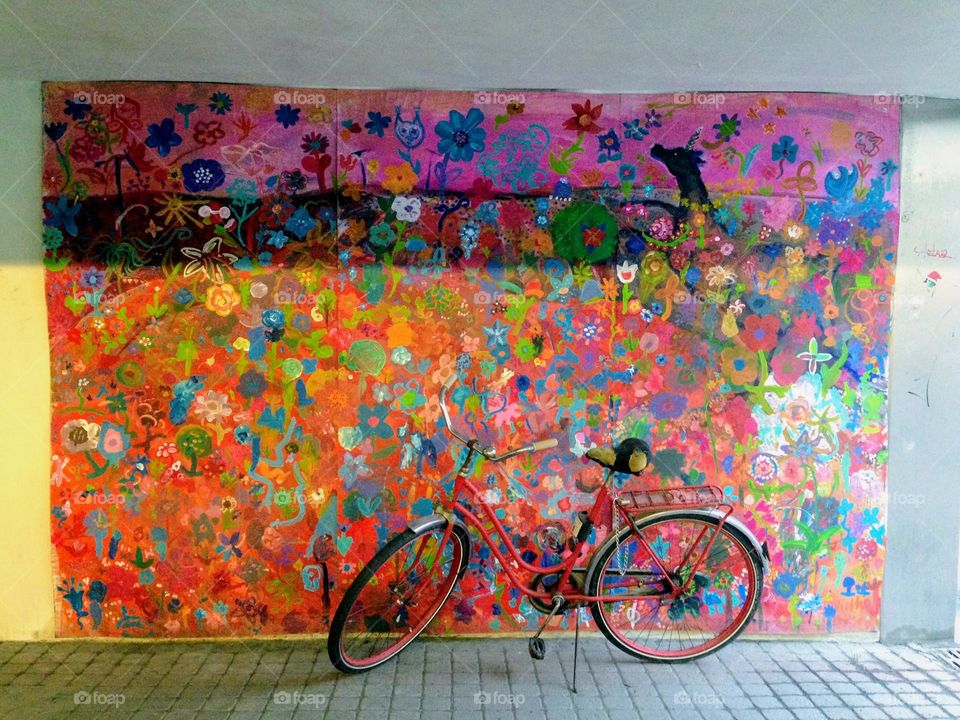 One lonely bicycle against the wall with bright multicoloured graffiti drawing 