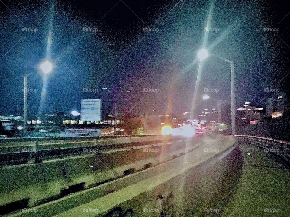 Cars with their headlights on zooming by at night on the Pulaski Bridge that connects Greenpoint, Brooklyn and Long Island City, Queens. New York. Photographed in October 2020. Hypnotic Productions