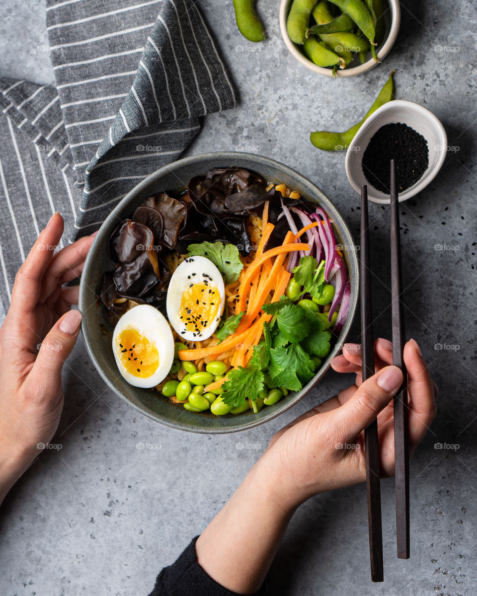 Female hands holding a bowl with Ramen noodles