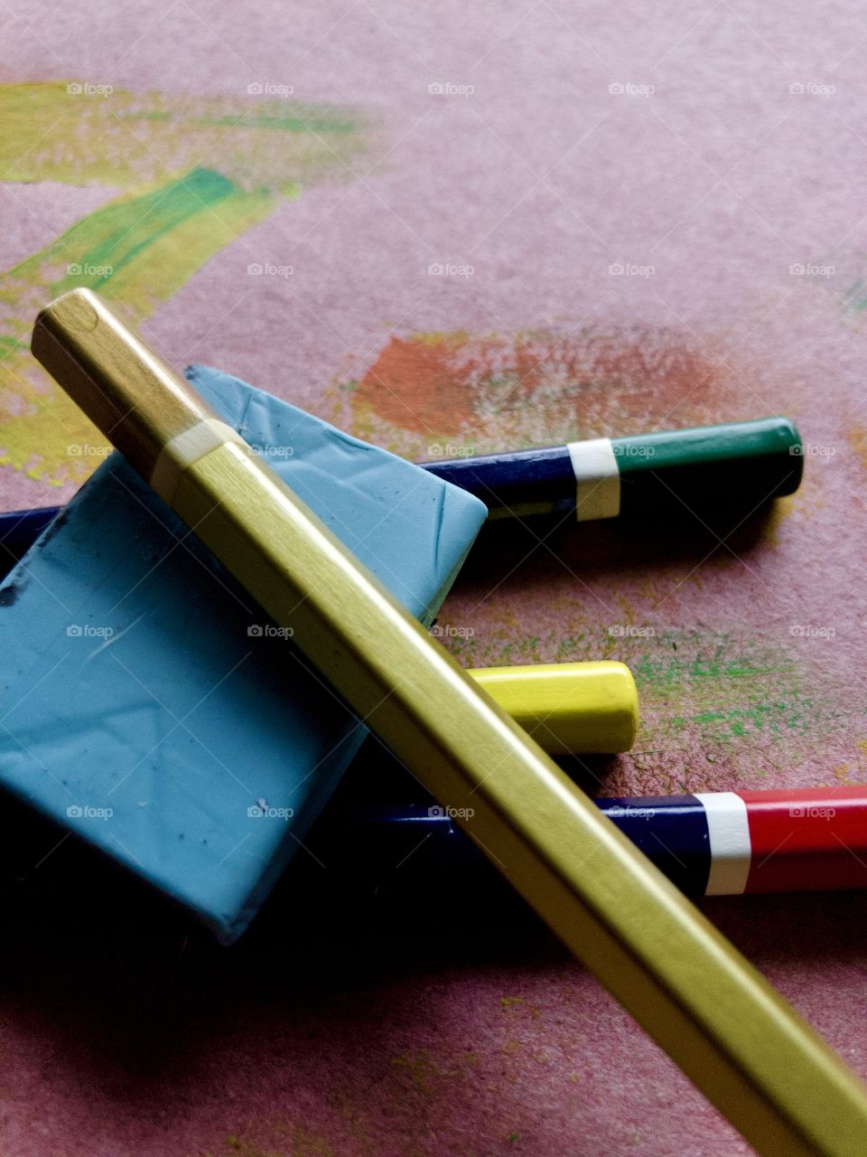 Kneaded eraser and colorful pencils on used craft paper with paint