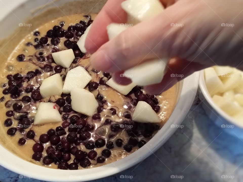 Woman's hand preparing a blueberry pear old fashioned cobbler for the oven