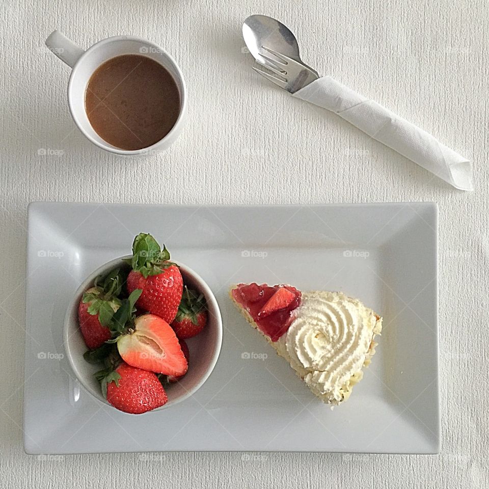 Having Slice of Freshcream cake and  fresh strawberries  and a cup of coffee 