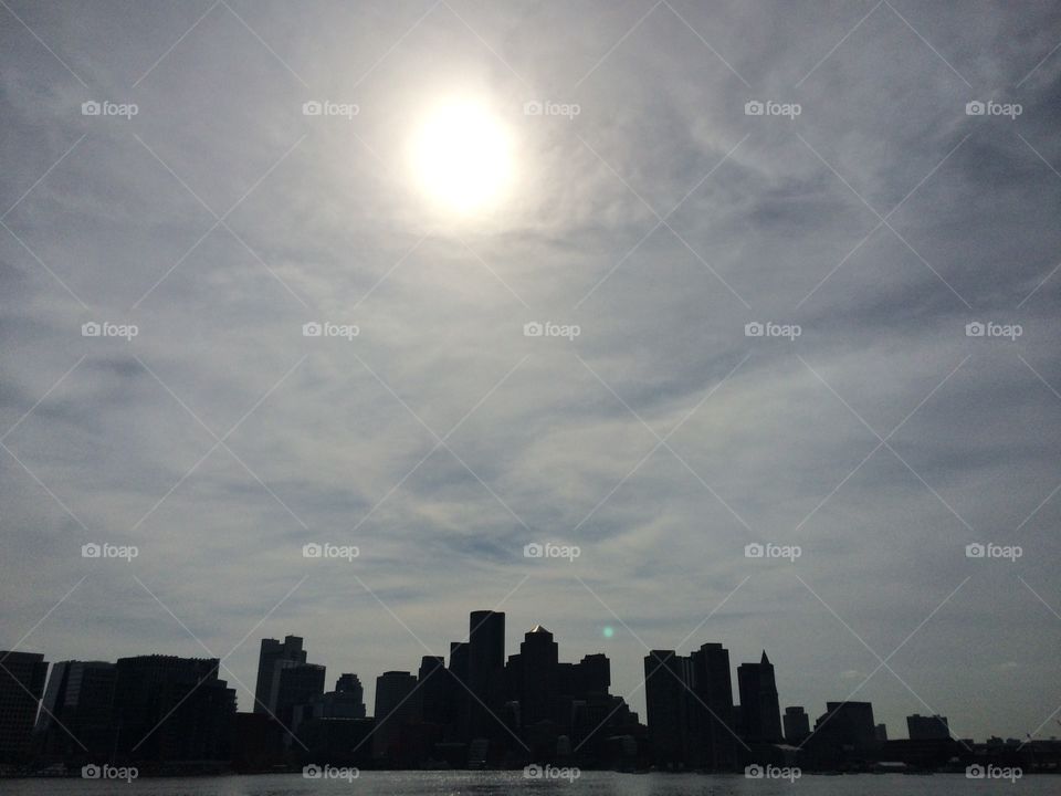 Silhouette city. Glaring sun in sky with cityscape below