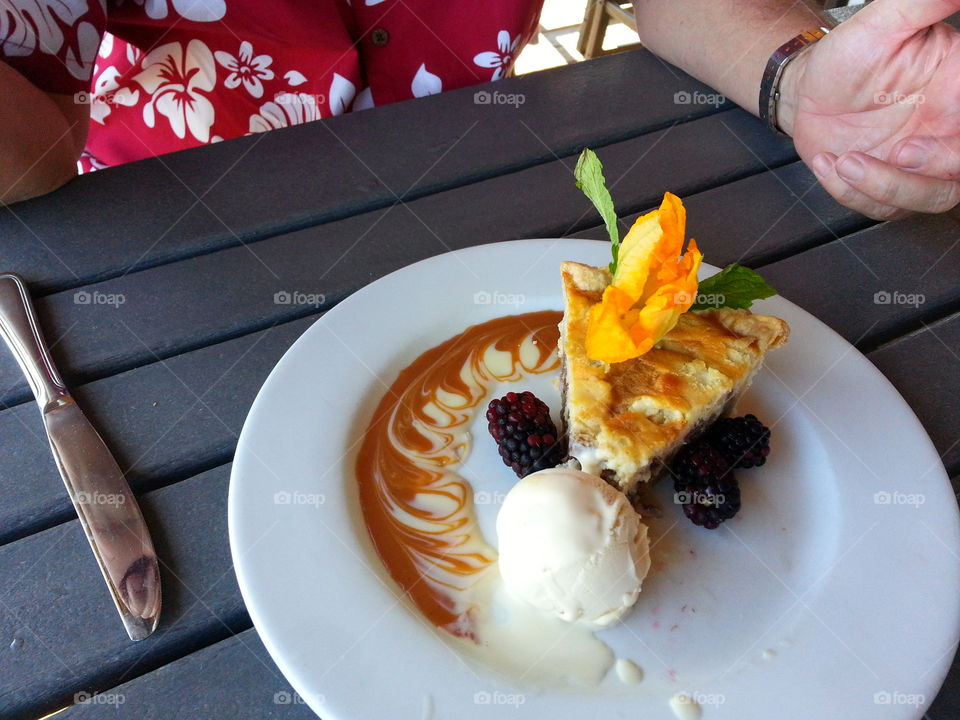 Gourmet dessert, pie ala mode with vanilla ice cream berries caramel swirl and a hibiscus flower on top