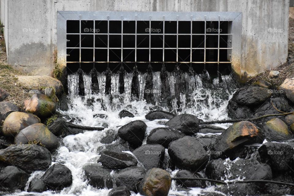 Water flows from a drain into rocks