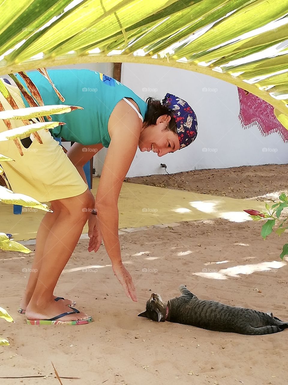 Woman playing with cat on sand 