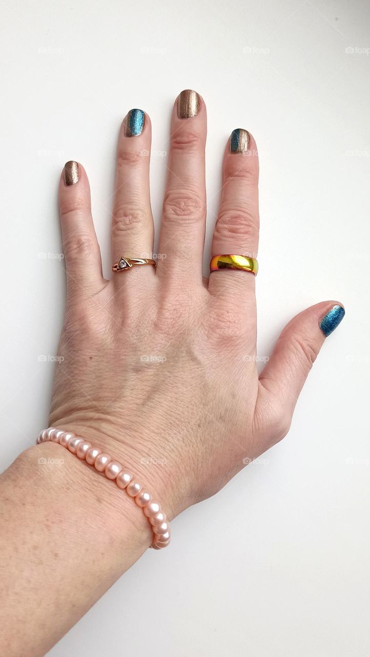 beautiful female hand with accessories rings and bracelet on a white background, beauty accessory