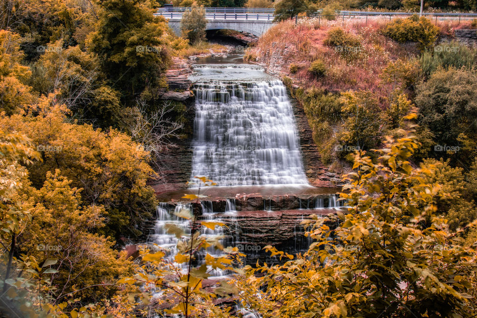 Summer turns to autumn as beautiful fall foliage colors take over a wooded area around a waterfall. 