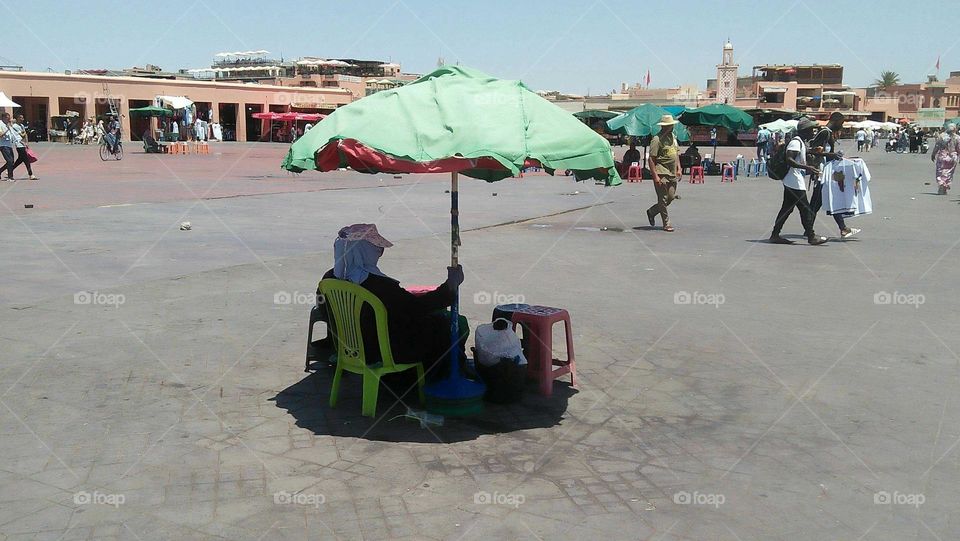 A woman under the umbrella in jaamlfna square in marrakech City in Morocco.