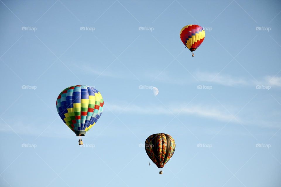 A trio of balloons rise into the sky around the coming moon.