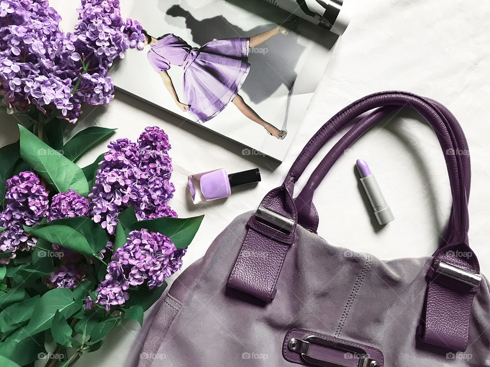 Flat lay pattern made of fashionable accessories, magazine and lilac flowers 