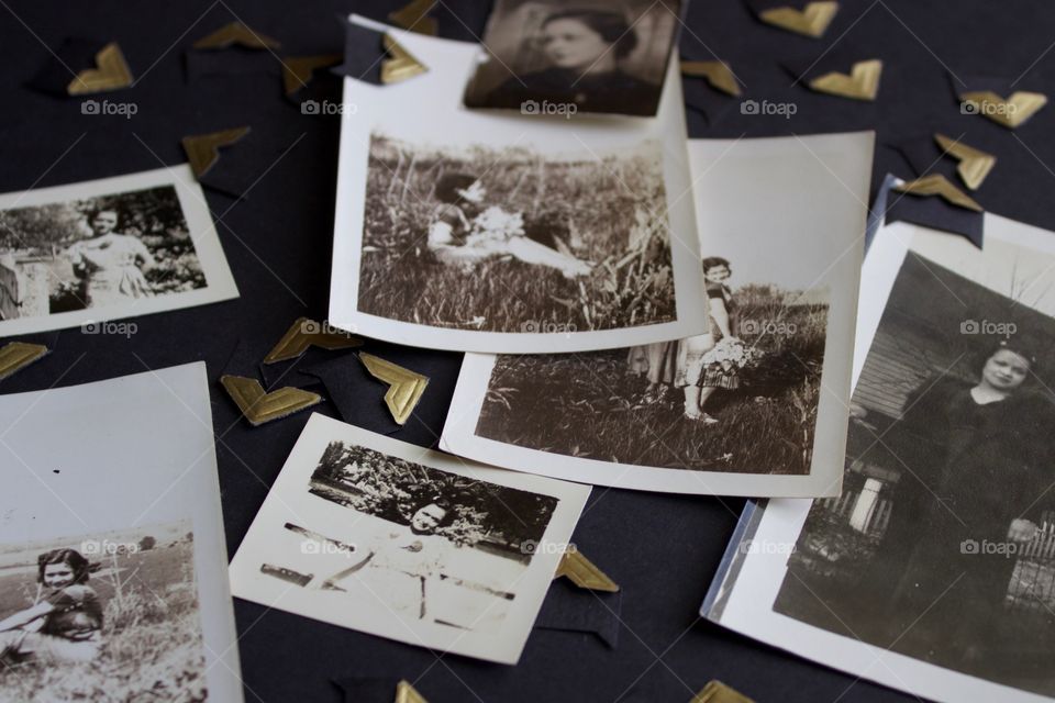 Vintage photo collection in black and white and sepia tones with gold photo mounting corners on a black surface 
