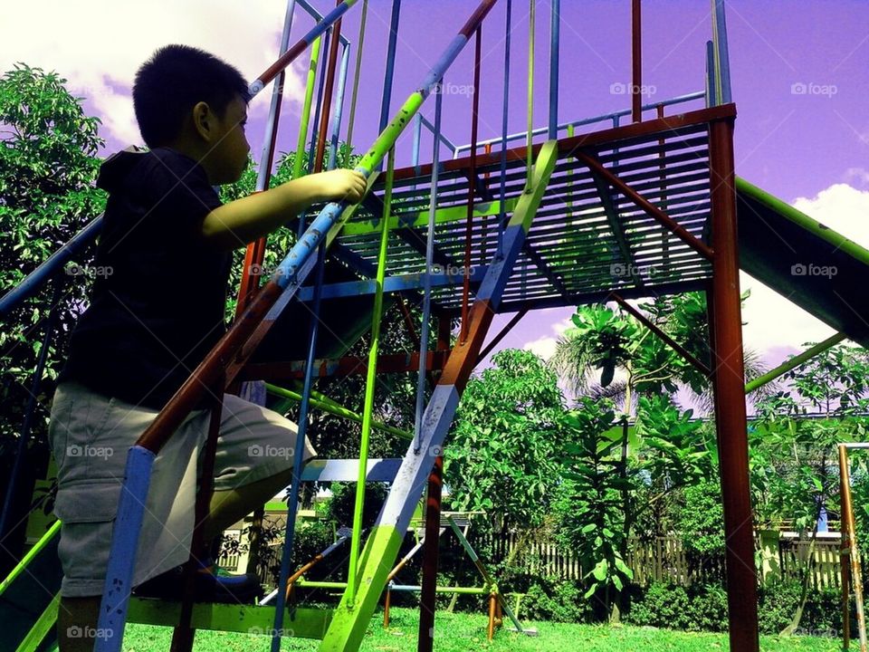 Boy climbing a slide in a park to play