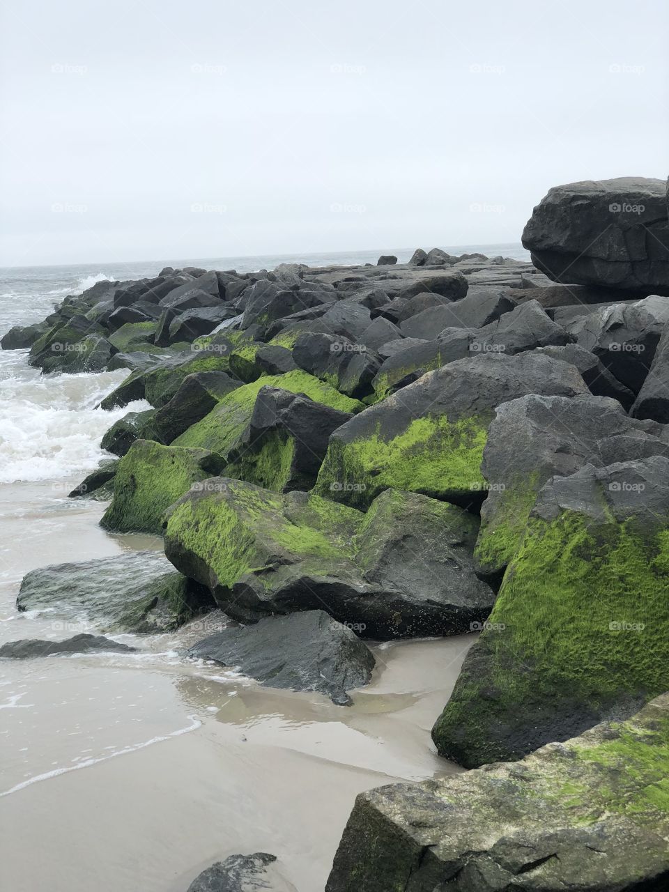 Angle view of the rock formation covered in moss located along the ocean waves 