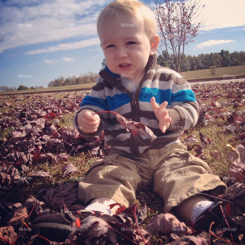 Funny face baby playing in the leaves